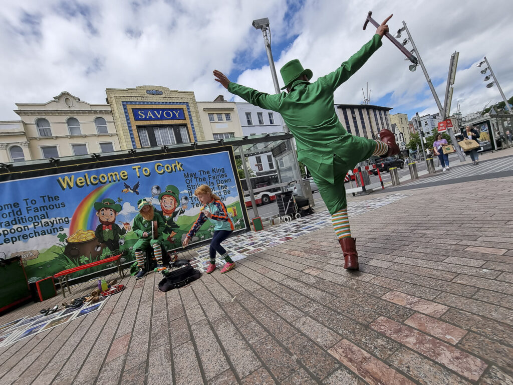 A leprechaun dances on the street.